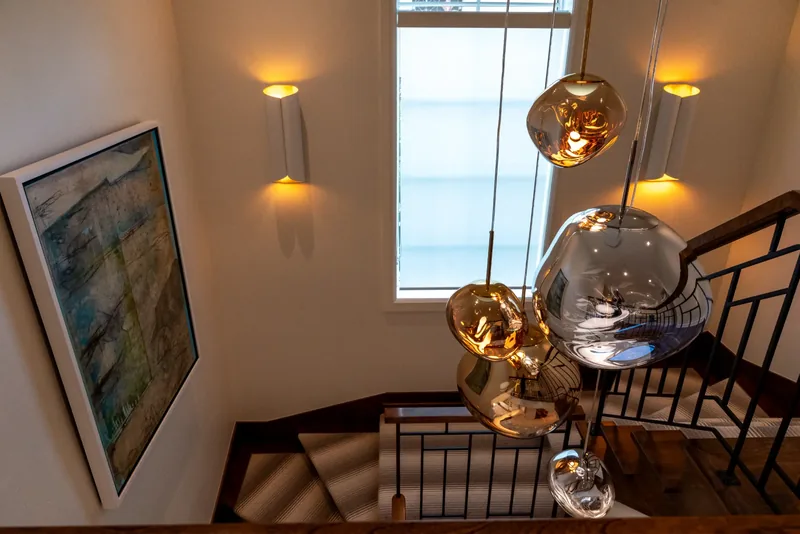 Cascade of glass globe pendants in the stairwell beneath an arched window