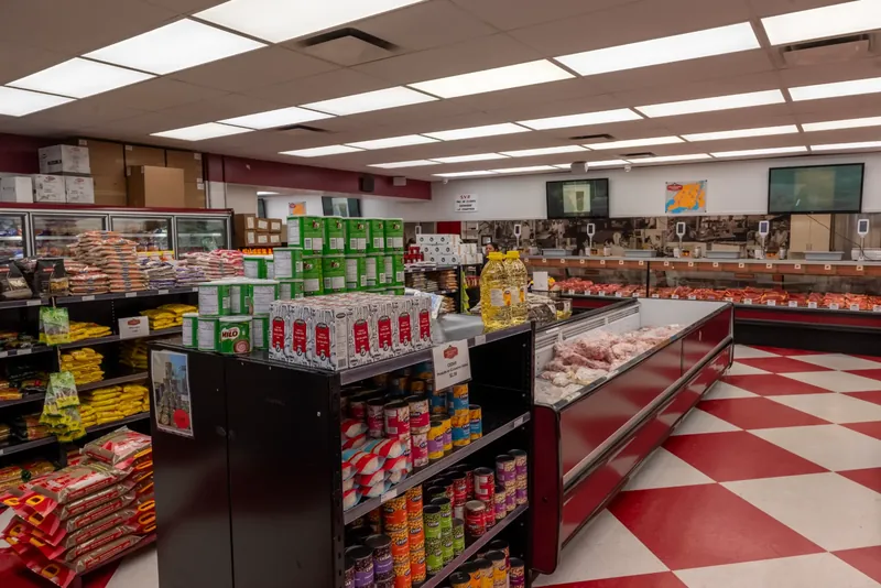 Grocery shelving and a refrigerated display case on a red-and-white checkered floor, with the butcher counter behind