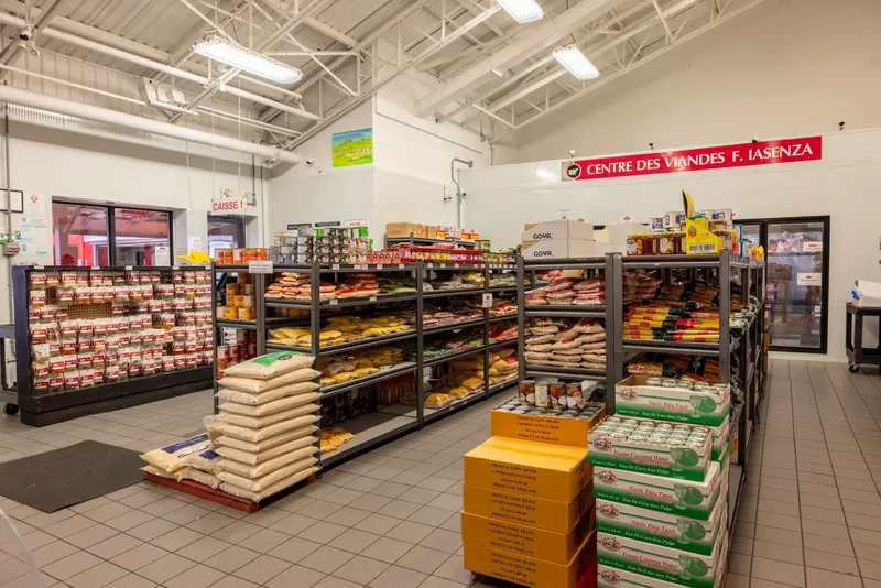 Grocery section under a high white open-web steel structure, with a tiled floor, shelving, and a checkout