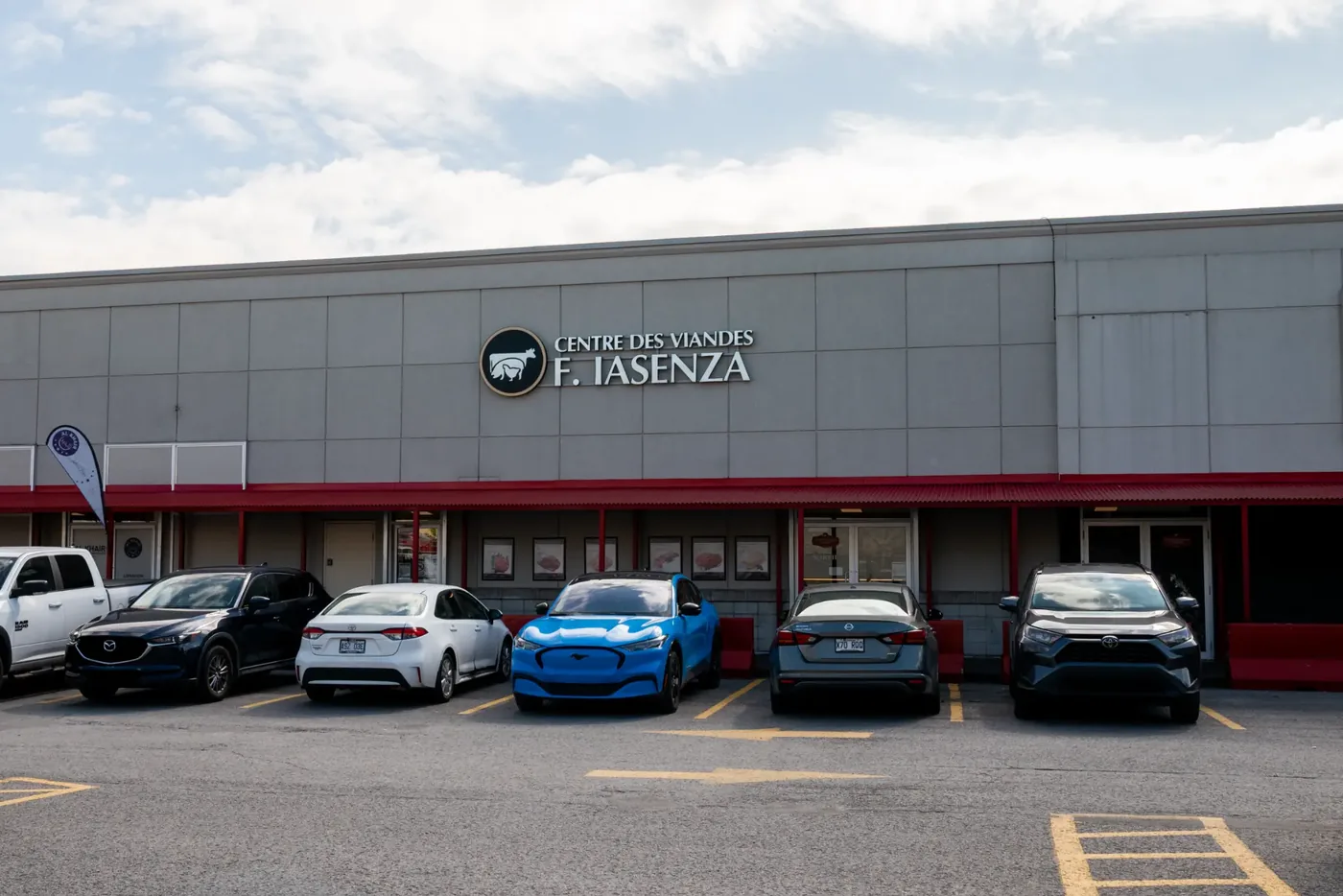 Large standalone Iasenza store clad in grey metal panels, with a red band, a logo sign, and a full parking lot