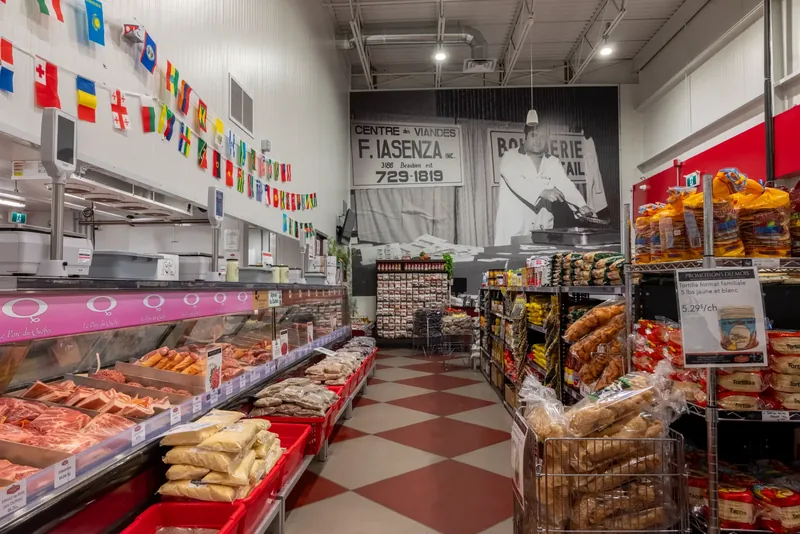 Long butcher counter under flag bunting, with a checkered floor and a large black-and-white photo mural from the company’s history