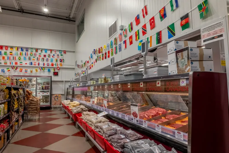 Refrigerated counter running the length of the store under rows of international flags, with glass-door freezers at the back