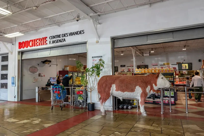 Shopping-centre entrance to an Iasenza butcher shop, with a large Boucherie sign and a life-size cow statue