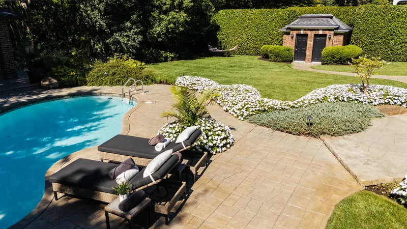 Aerial view of lounge chairs on the stone terrace, the lawn, and the garden pavilion beyond