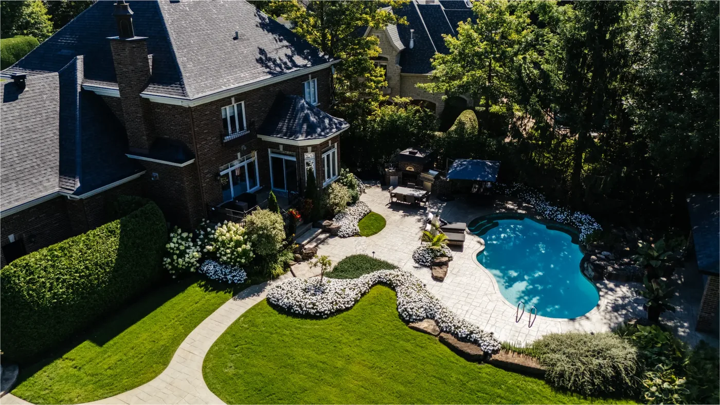 Aerial view of the brick residence, its landscaped rear garden, and the terrace