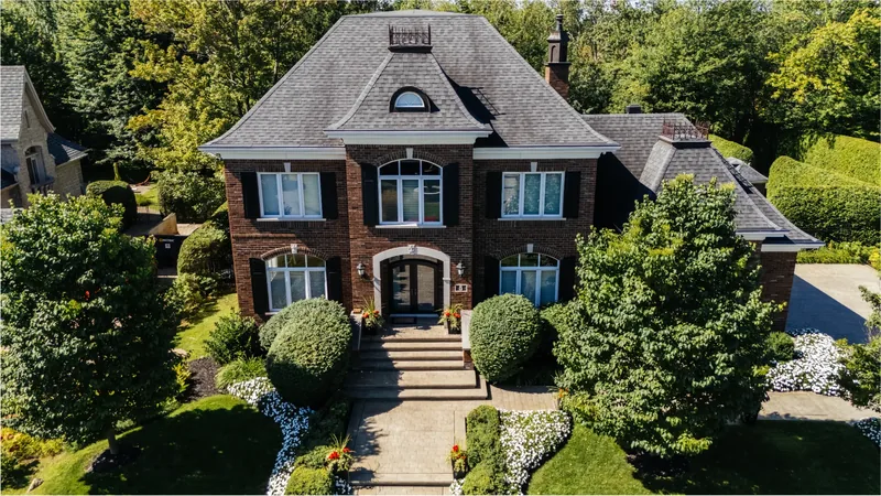 Front of the brick residence with stone steps, clipped boxwood, and flower beds