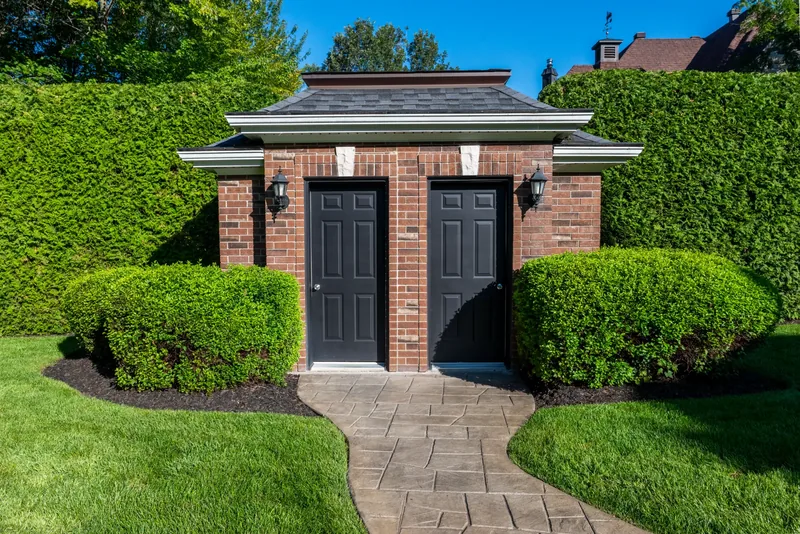 Brick garden pavilion framed by tall cedar hedges