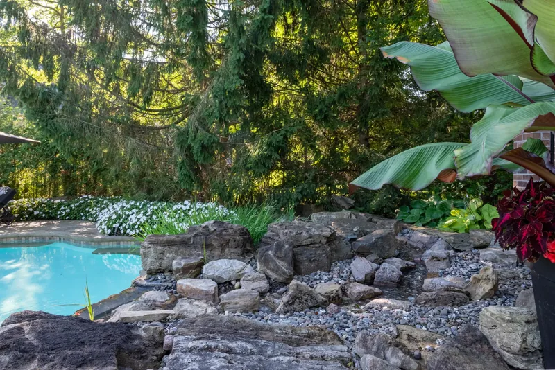 Natural boulder rock garden with tropical foliage at the water’s edge