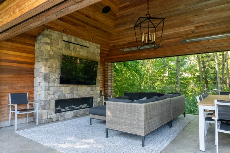 Pavilion with a cedar ceiling, a stacked-stone fireplace wall, and a lantern chandelier