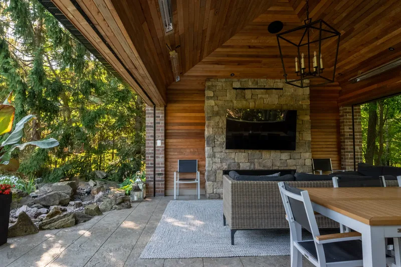 Pavilion with a cedar ceiling, a stacked-stone fireplace wall, and a lantern chandelier