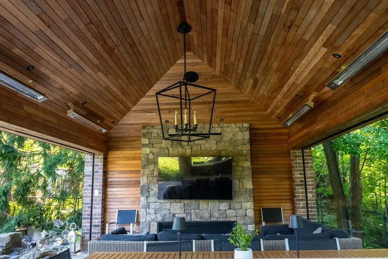 Pavilion with a cedar ceiling, a stacked-stone fireplace wall, and a lantern chandelier