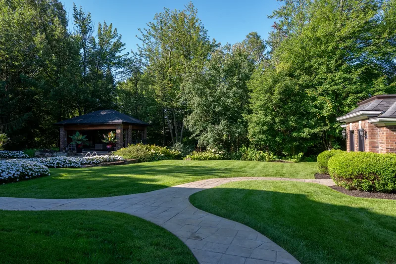 Curving walkway across a wide lawn toward the cedar pavilion