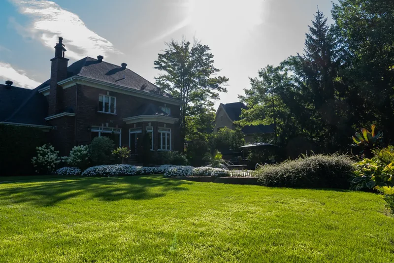 Wide lawn and mature trees behind the brick residence