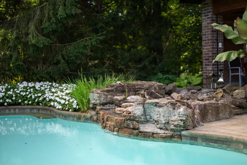 Natural boulder rock garden with tropical foliage at the water’s edge