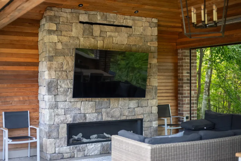 Pavilion with a cedar ceiling, a stacked-stone fireplace wall, and a lantern chandelier