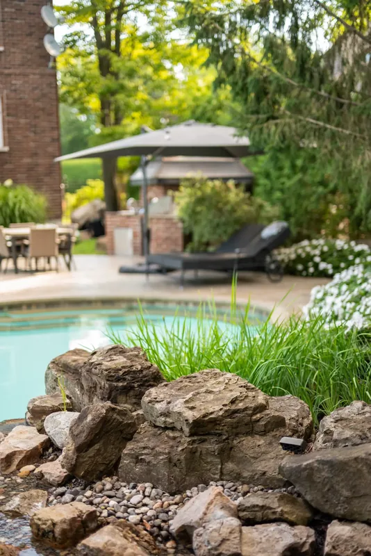 Natural boulder rock garden with tropical foliage at the water’s edge