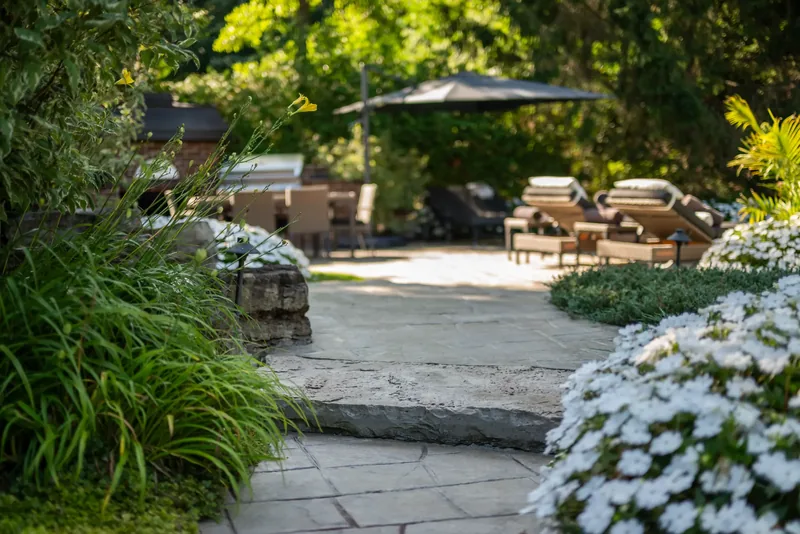 Stone paving, natural stone steps, and lush plantings around the terrace
