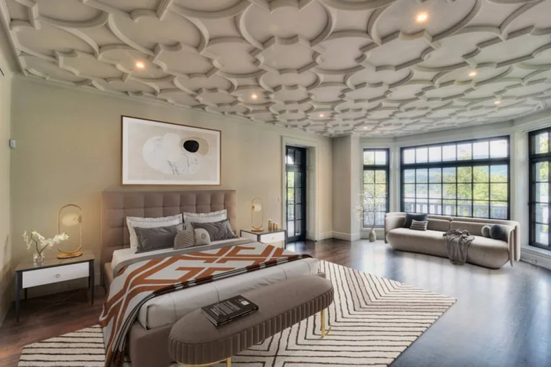 Bedroom with a sculpted ceiling, a seating area, and windows overlooking the lake