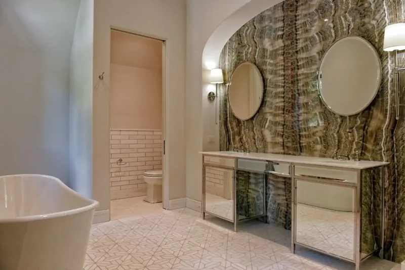 Bathroom with a freestanding tub, round mirrors, and a feature wall of patterned stone