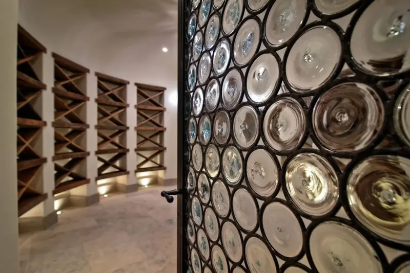 Wine cellar door in leaded bullseye glass, opening onto lit wood racks