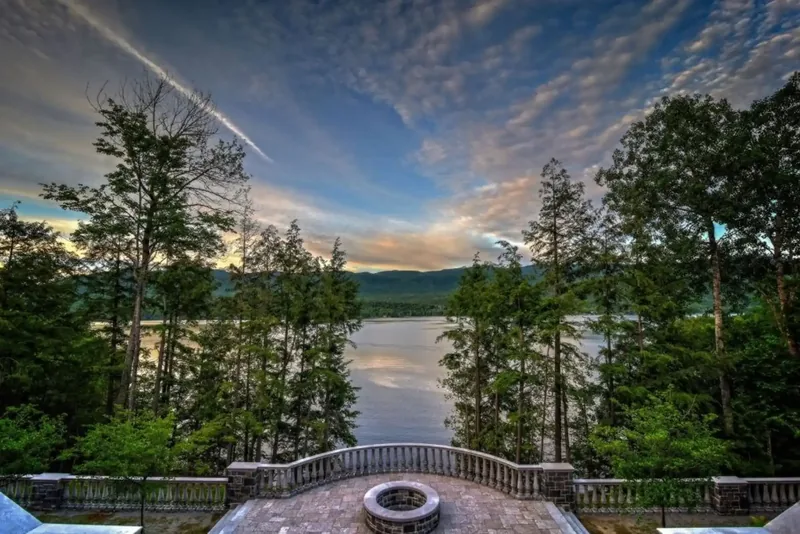 Stone terrace with a fire pit overlooking the lake and mountains at sunset
