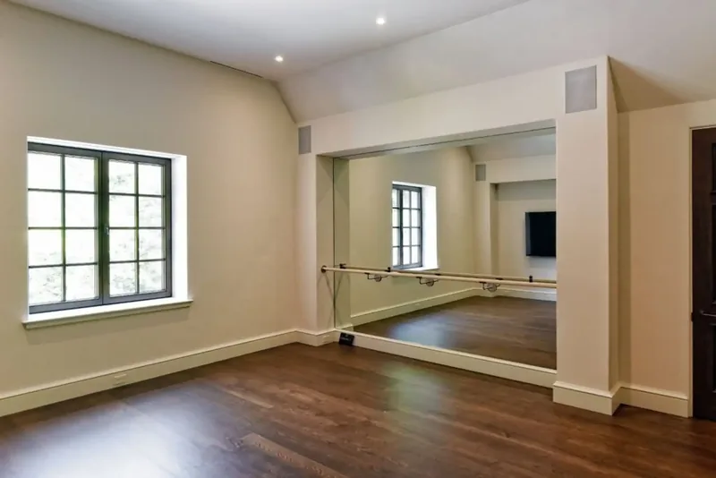 Fitness room with a ballet barre, a mirrored wall, and windows on the trees