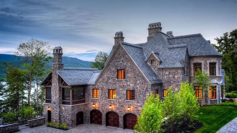 Stone facade at dusk with slate roofs, tall chimneys, and three arched garage doors