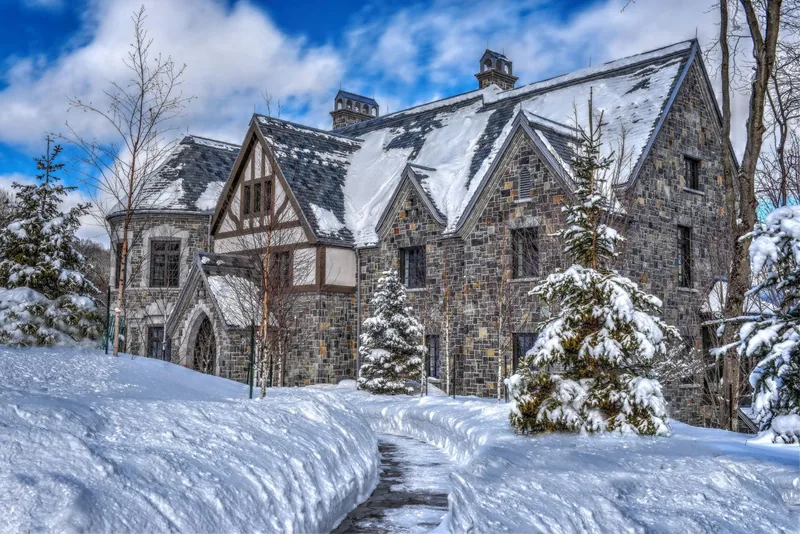 Stone and half-timbered facade under fresh snow, with steep gabled slate roofs