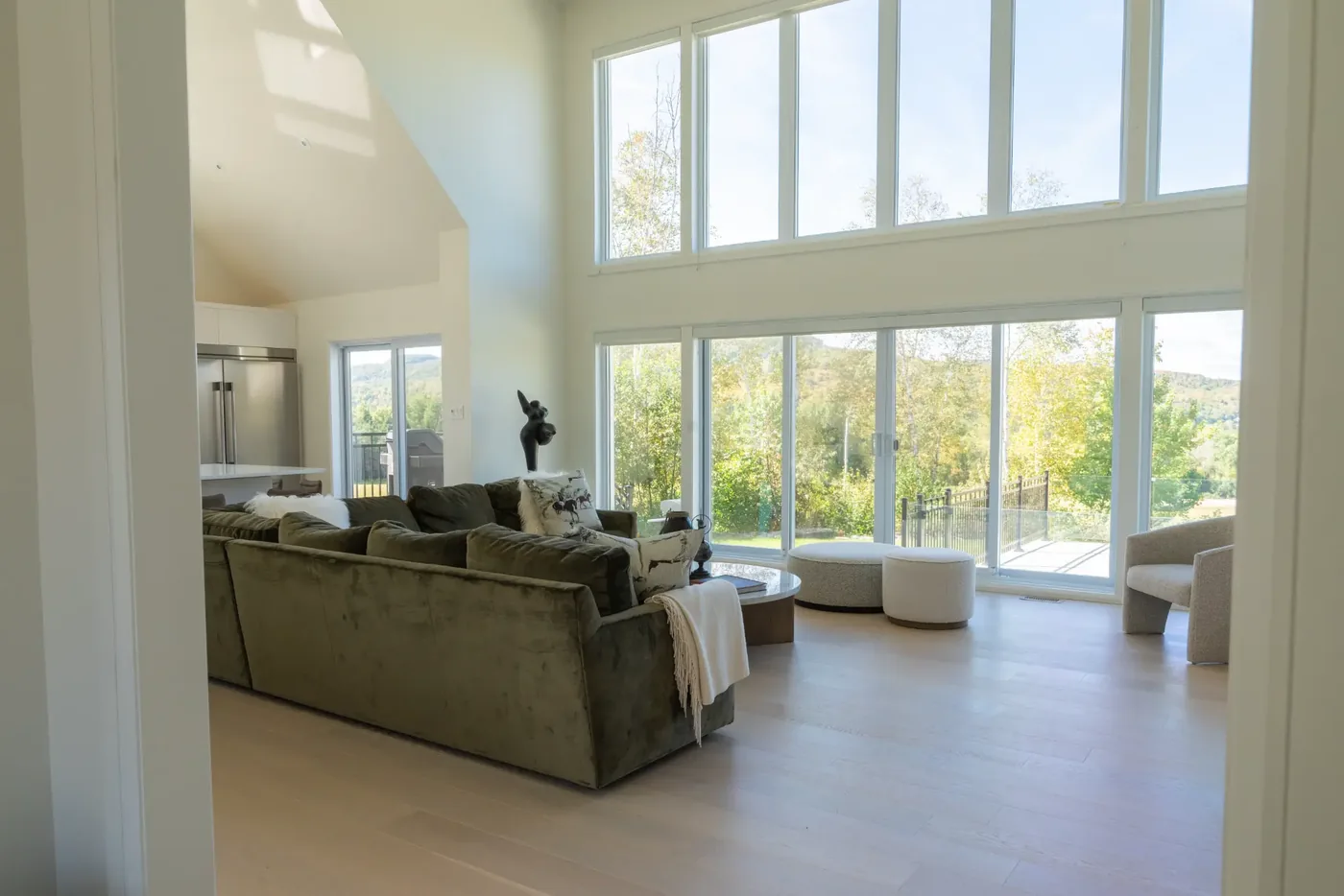 Great room with a cathedral ceiling, double-height windows, and an olive velvet sectional