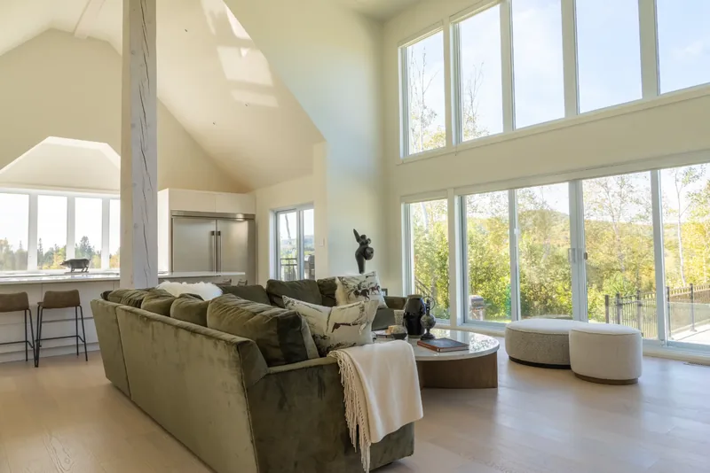 Great room with a cathedral ceiling, double-height windows, and an olive velvet sectional