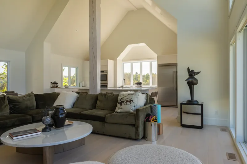 Olive velvet sectional, oval coffee table, and black sculptures in the great room