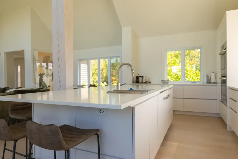 Kitchen with a large white island, bar stools, and handleless white cabinetry