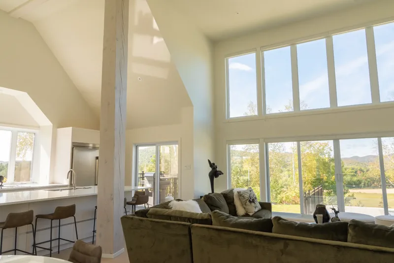 Great room seating beneath walls of windows overlooking the forest and hills