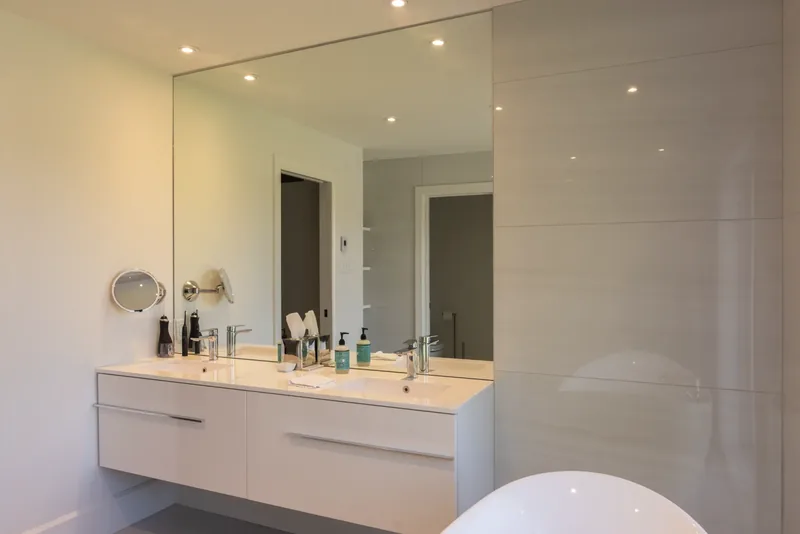 Floating double vanity beneath a wide wall mirror