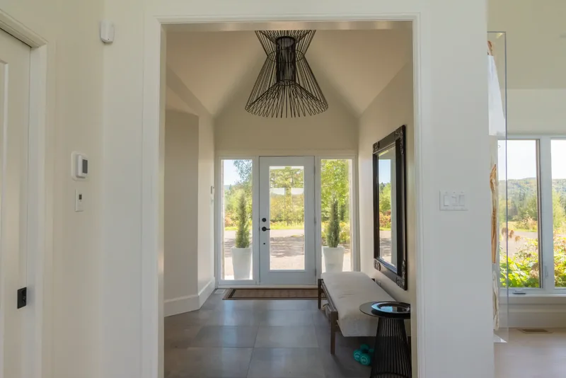 Foyer with double glass doors, a black sculptural pendant, and a large ornate mirror