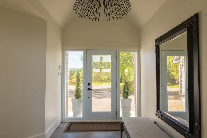 Foyer with double glass doors, a black sculptural pendant, and a large ornate mirror