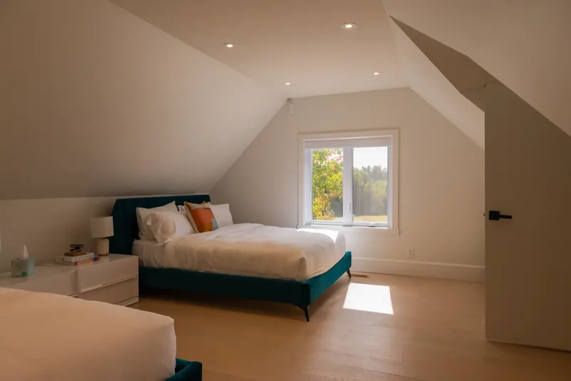Upper-floor bedroom with a teal velvet bed beneath sloped ceilings