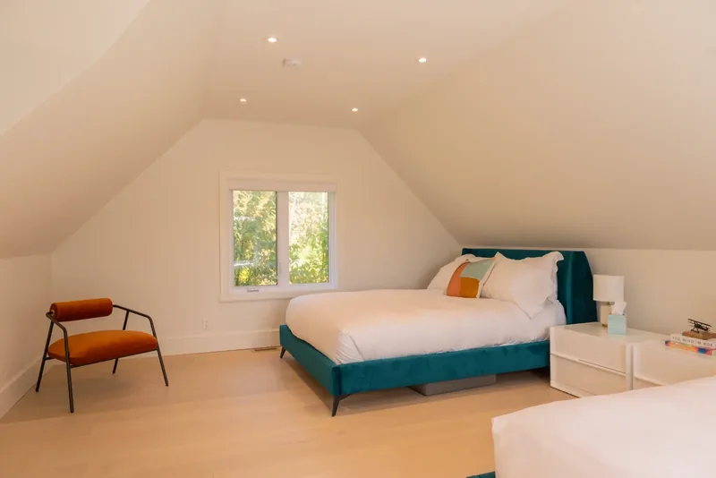 Upper-floor bedroom with a teal velvet bed beneath sloped ceilings