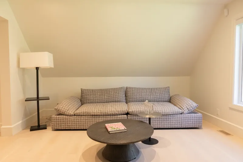 Upper-floor lounge with a sofa, a round black coffee table, and dormer windows