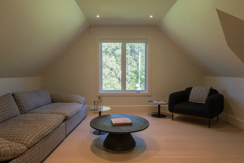 Upper-floor lounge with a sofa, a round black coffee table, and dormer windows