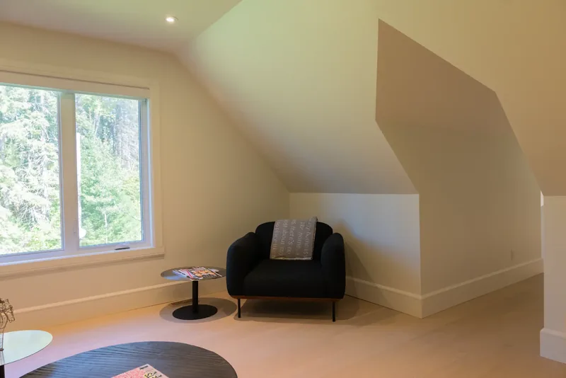 Upper-floor lounge with a sofa, a round black coffee table, and dormer windows