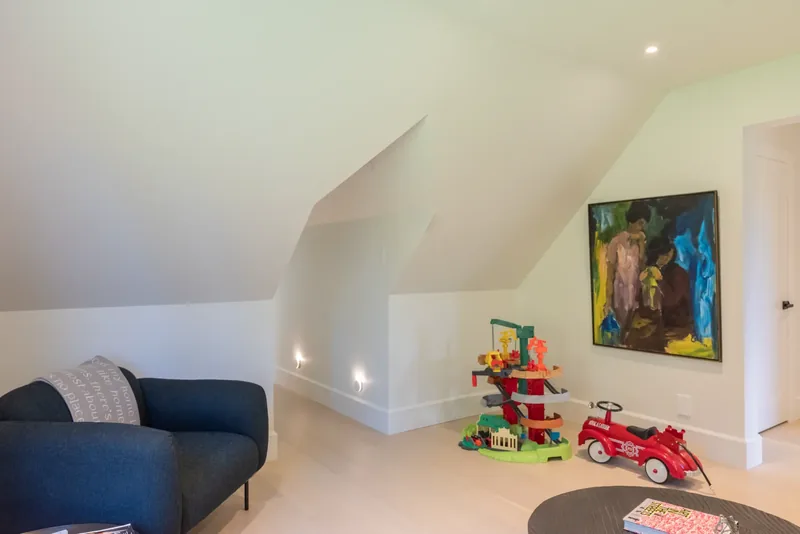 Playroom with a sofa, toys, and colourful artwork beneath sloped ceilings