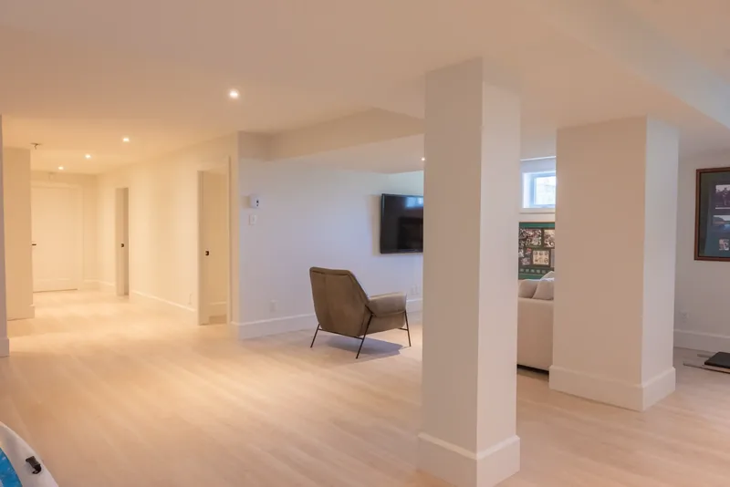Lower-level family room with white columns and an armchair