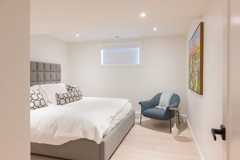 Lower-level bedroom with a tufted headboard and an armchair