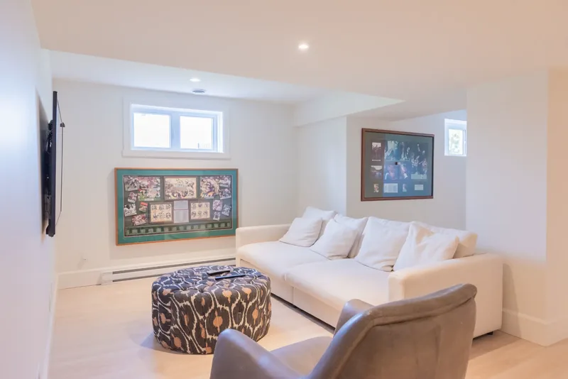 Lower-level lounge with a white sofa and a patterned ottoman