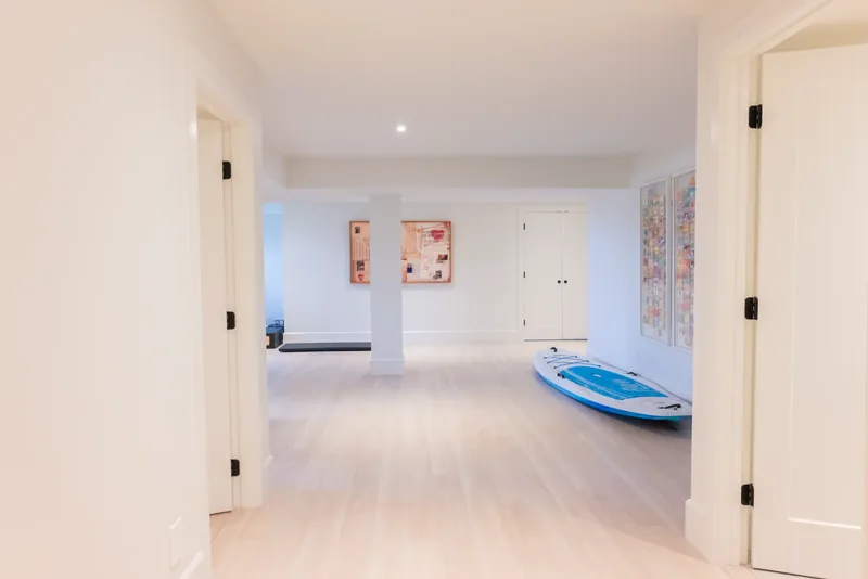 Open lower-level space with white oak floors and artwork