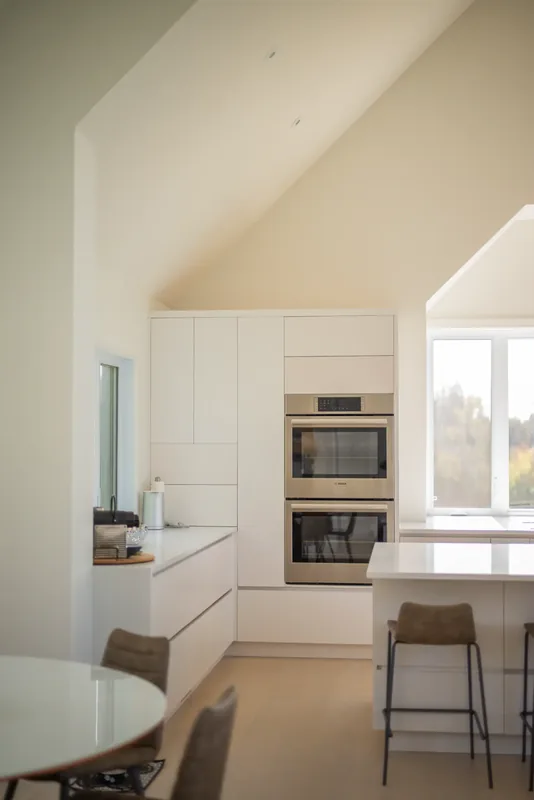 Double wall ovens and tall white cabinetry beside the island