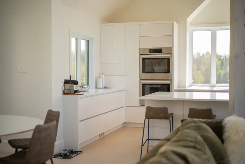 Double wall ovens and tall white cabinetry beside the island