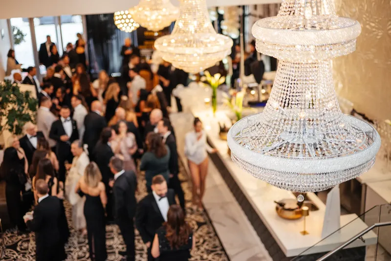 Cocktail reception seen from above, with large crystal chandeliers over a long white bar